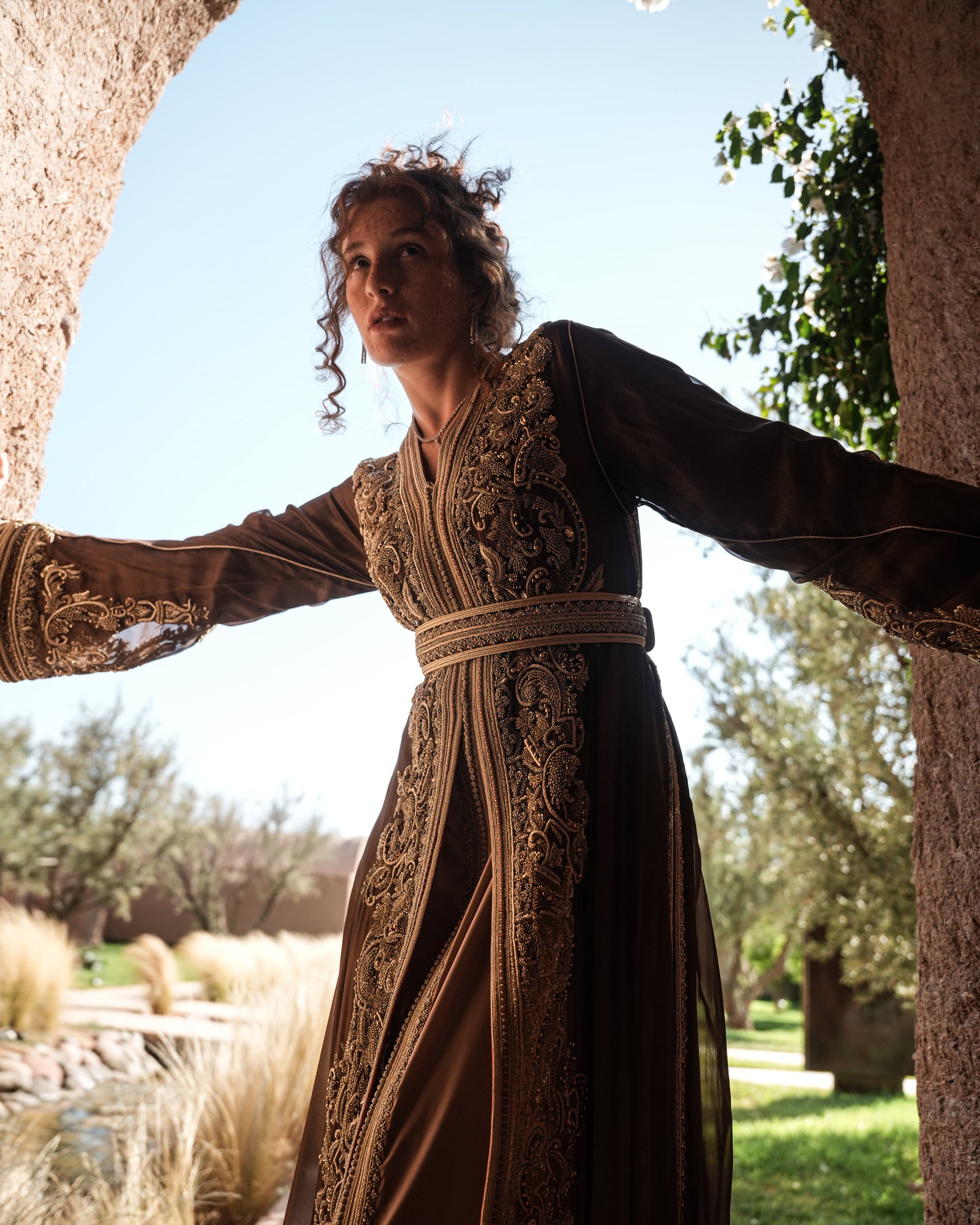 Bronze Reverie lamé organza Moroccan kaftan with gold embroidery, worn open over a champagne dress