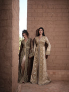 Bronze Reverie lamé organza Moroccan kaftan with gold embroidery, worn open over a champagne dress, shown alongside a second look