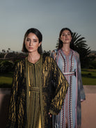 Onyx Serenade fringed black lace Moroccan kaftan over a mustard-gold dress, shown alongside a second look